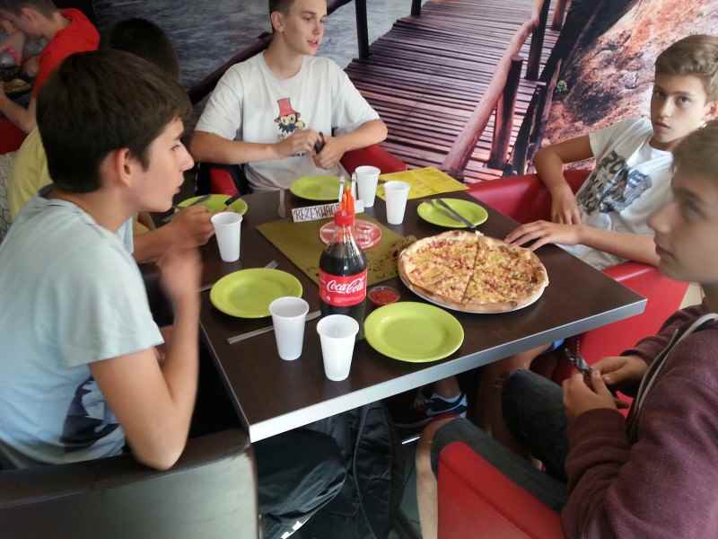 chłopcy jedzą pizzę